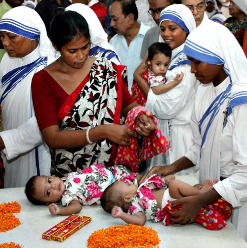 MC nuns and maids bring orphans to the tomb of Mother Teresa after carrying them around the coffin of Sr Nirmala Joshi (seen behind) ahead of the funeral at the Mother House in Kolkata on June 24, 2015.<br />